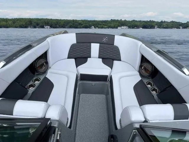 Slide: The Image of 2024 MasterCraft X24 boat interior with luxurious seating on a serene lake. - 5