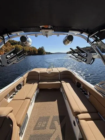 Slide: The Image of 2019 MasterCraft XT25 boat interior with tan seating, lake view, and wakeboard racks. - 4