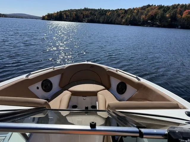 Slide: The Image of 2019 MasterCraft XT25 boat on a serene lake with scenic forested shoreline. - 5