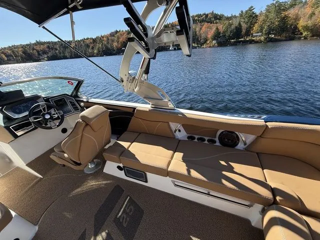 Slide: The Image of 2019 MasterCraft XT25 boat interior with tan seating, steering wheel, and lake view. - 8