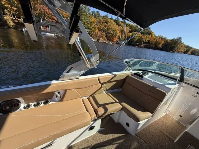 Slide: The Image of 2019 MasterCraft XT25 boat interior with tan seating, on a scenic lake with autumn trees. - 9