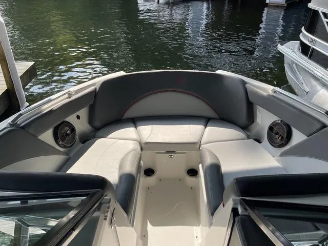 Slide: The Image of 2019 MasterCraft XT22 boat interior with gray seating and speakers, docked on calm water. - 11