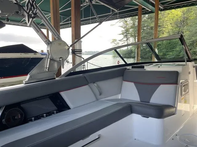 Slide: The Image of 2019 MasterCraft XT22 boat interior with gray seating under a canopy by the water. - 12