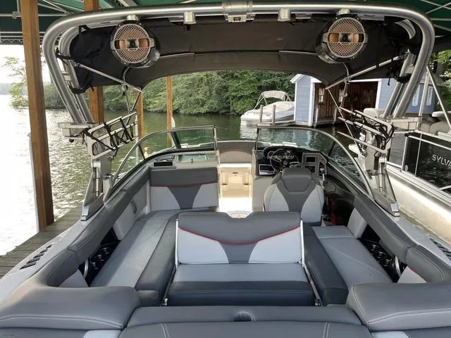 Slide: The Image of 2019 MasterCraft XT22 boat interior with seating, speakers, and steering wheel, docked by a lake. - 15