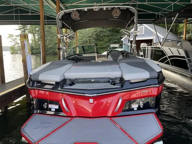 Slide: The Image of 2019 MasterCraft XT22 boat docked under a canopy, featuring sleek red and gray design. - 2