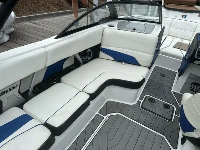 Slide: The Image of 2017 Malibu 24 MXZ boat interior with white and blue seating, gray flooring. - 13