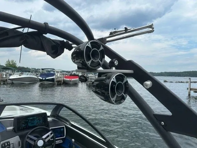 Slide: The Image of 2017 Malibu 24 MXZ boat with speakers and control panel, docked by a lake. - 15