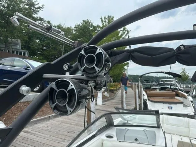 Slide: The Image of 2017 Malibu 24 MXZ boat with speakers docked at a marina. - 16