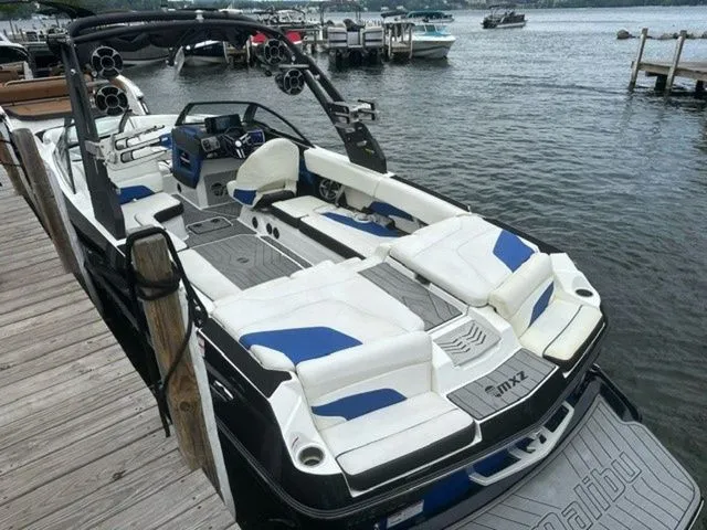 Slide: The Image of 2017 Malibu 24 MXZ boat docked, featuring sleek design and spacious seating. - 18