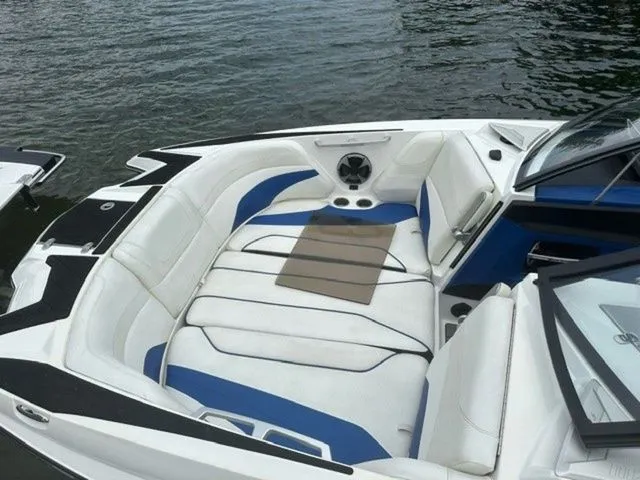Slide: The Image of 2017 Malibu 24 MXZ boat interior with white and blue seating, on calm water. - 7