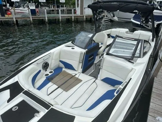 Slide: The Image of 2017 Malibu 24 MXZ boat with white and blue interior, docked by the water. - 8