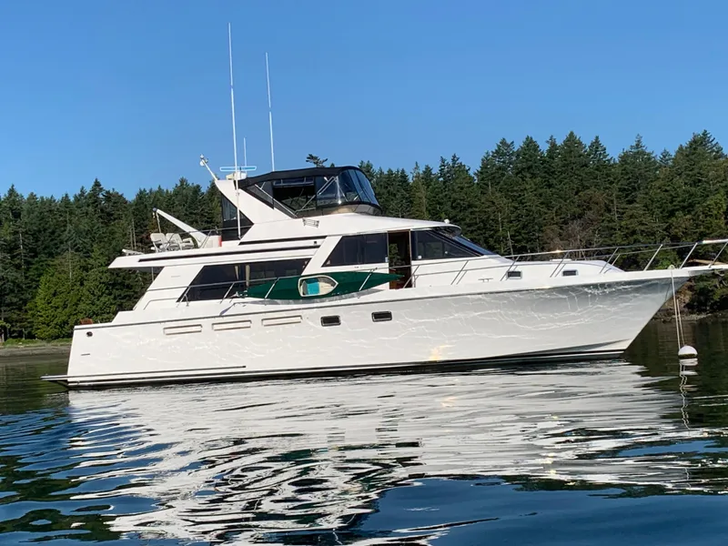 The Image of 1997 Ocean Alexander 548 yacht on calm water with forested background. - 0