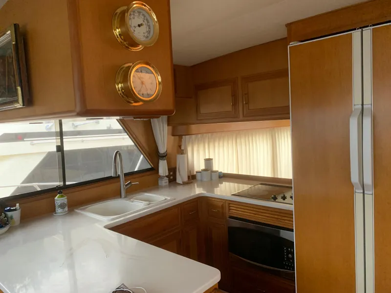 Slide: The Image of 1997 Ocean Alexander 548 yacht kitchen with wood cabinetry, modern appliances, and nautical decor. - 13