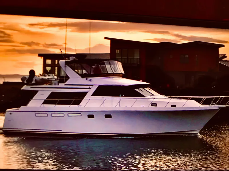 Slide: The Image of 1997 Ocean Alexander 548 yacht cruising at sunset near modern waterfront buildings. - 3