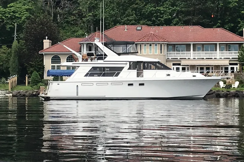 Slide: The Image of Ocean Alexander 548 yacht, 1997 model, docked near a waterfront house with lush greenery. - 5