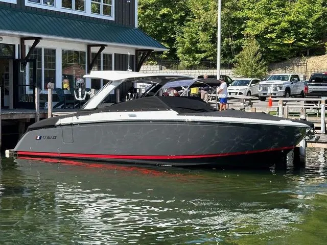 Slide: The Image of 2024 Cobalt R33 Surf boat docked by a lakeside building. - 1