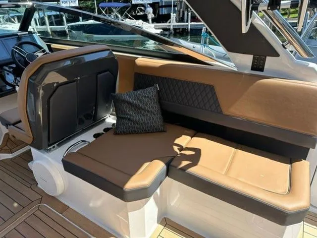 Slide: The Image of 2024 Cobalt R33 Surf boat interior with brown leather seating and decorative pillow. - 13