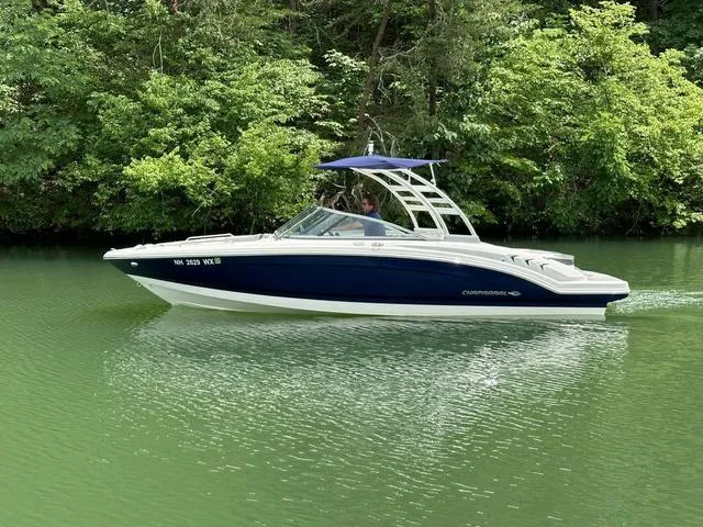Slide: The Image of 2023 Chaparral 23 SSi boat cruising on a serene, green river with lush forest backdrop. - 7