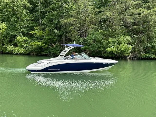 Slide: The Image of 2023 Chaparral 23 SSi boat cruising on a serene green lake surrounded by lush trees. - 10