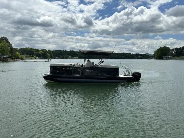 Slide: The Image of 2023 Sylvan Mirage X3 pontoon boat on a serene lake under a cloudy sky. - 7
