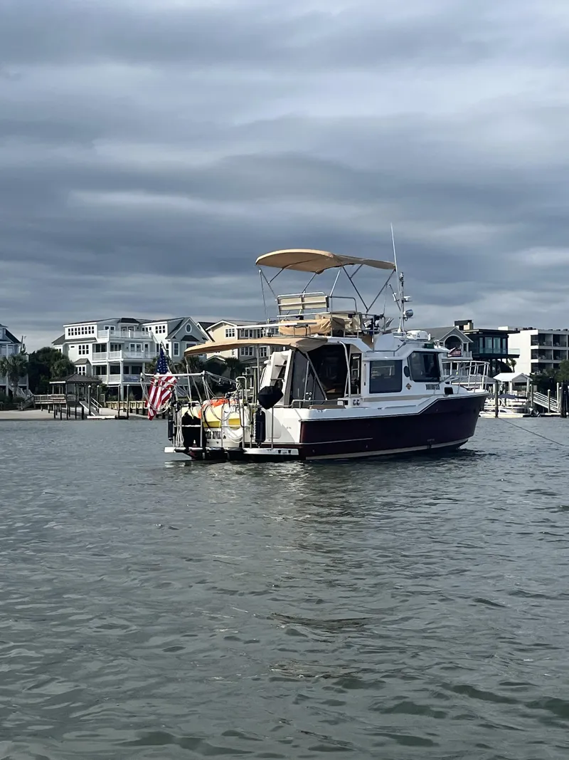Slide: The Image of 2019 Ranger Tugs R-29 CB boat on water near waterfront homes under cloudy sky. - 1