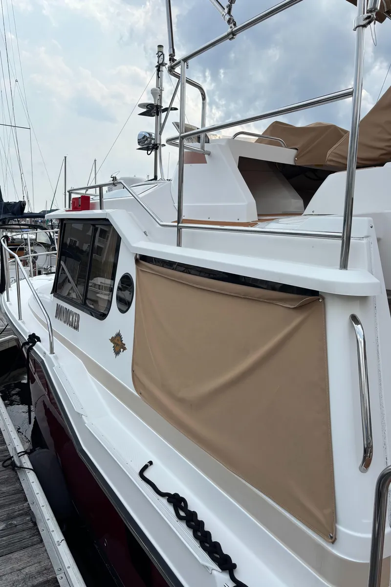 Slide: The Image of 2019 Ranger Tugs R-29 CB boat docked, featuring sleek design and beige cover. - 13