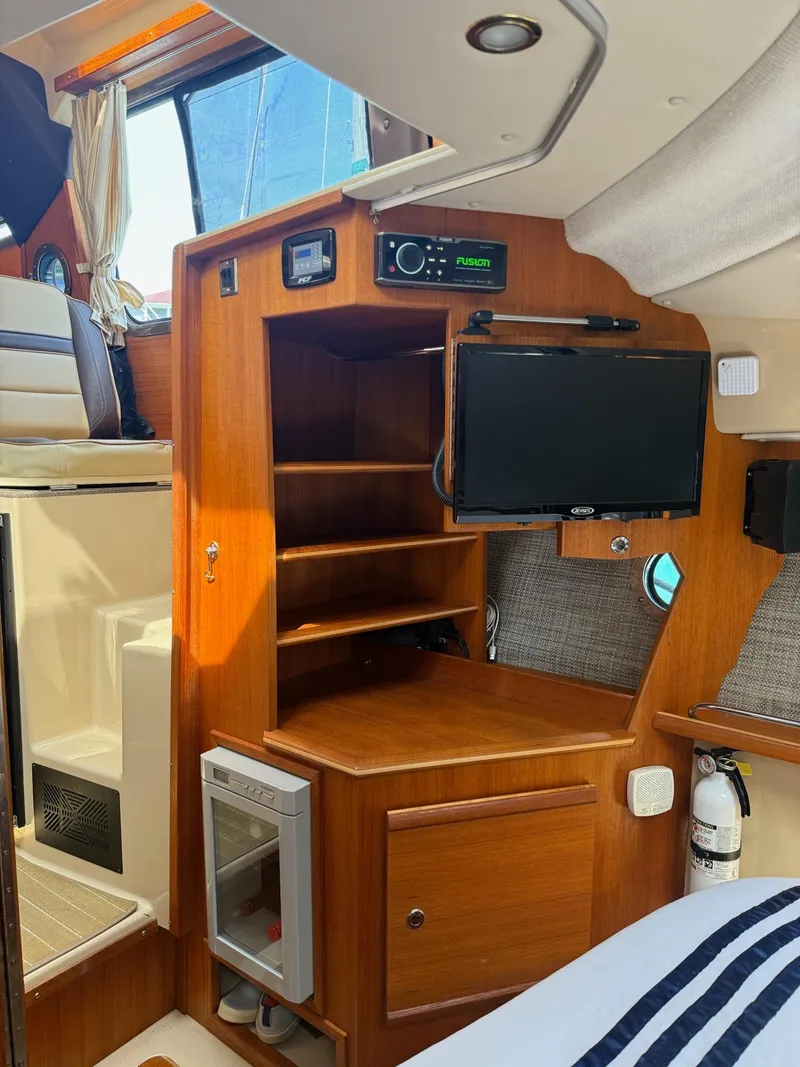 Slide: The Image of 2019 Ranger Tugs R-29 CB interior with wooden cabinetry, TV, and compact fridge. - 37