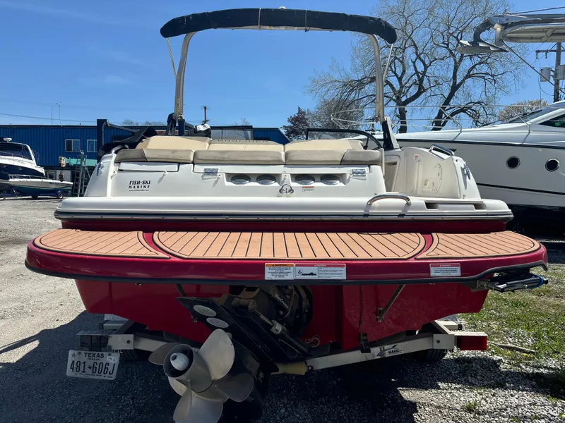 Slide: The Image of 2016 Bayliner 215 Deck Boat with red hull and swim platform, parked outdoors. - 11