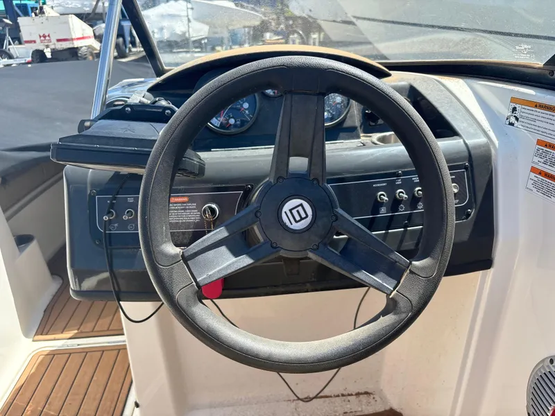 Slide: The Image of Steering wheel of a 2016 Bayliner 215 Deck Boat with dashboard controls. - 5