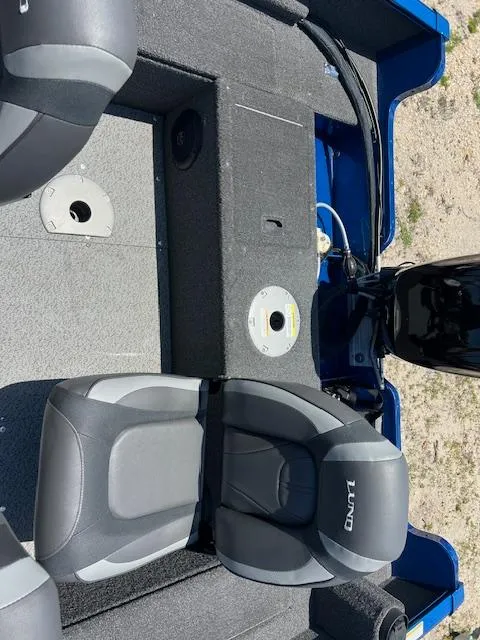 Slide: The Image of 2022 Lund 1650 Angler SS boat interior with seating and motor, on sandy terrain. - 2