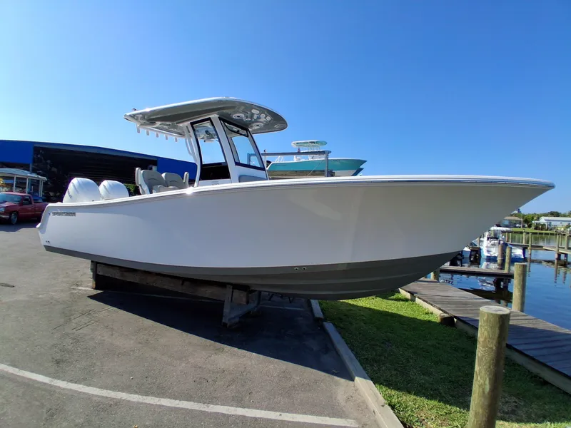 Slide: The Image of 2025 Sportsman Open 252 Center Console boat docked near a marina under clear blue skies. - 2