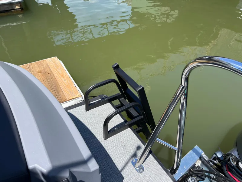 Slide: The Image of 2025 Starcraft GX 22 R DH Sport boat ladder and railing by the water. - 16