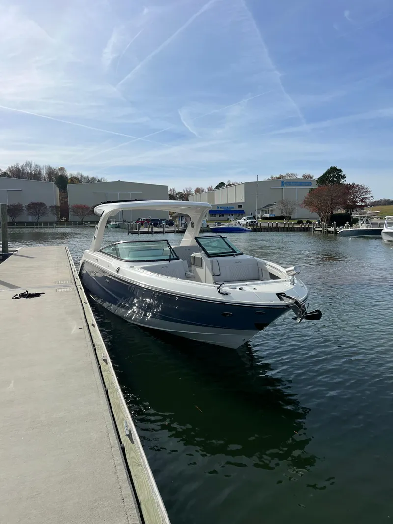 Slide: The Image of 2023 Sea Ray SLX 310 OB docked at a marina under a clear blue sky. - 10