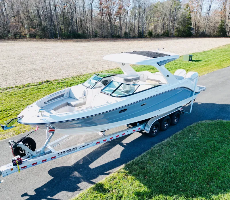 Slide: The Image of 2023 Sea Ray SLX 310 OB boat on trailer, parked on a paved road. - 2