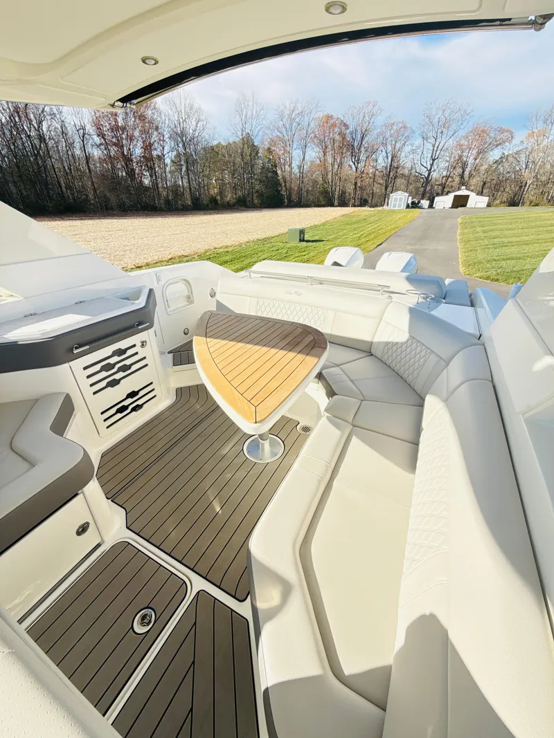 Slide: The Image of 2023 Sea Ray SLX 310 OB boat interior with sleek seating and wooden table. - 42