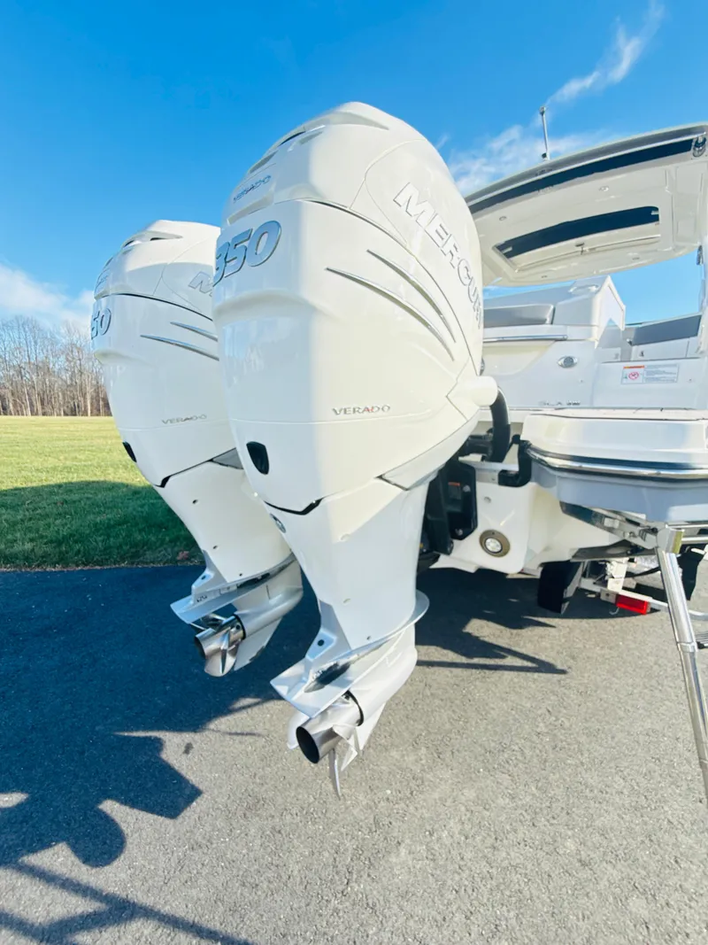 Slide: The Image of 2023 Sea Ray SLX 310 OB with dual outboard engines, parked on pavement. - 7