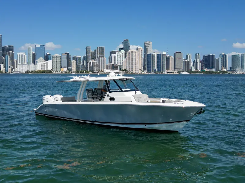 The Image of 2023 Pursuit S358 boat cruising near a city skyline on a sunny day. - 1