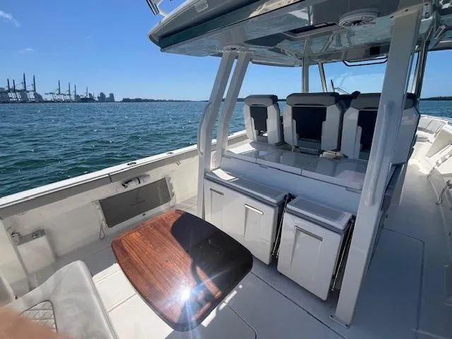 Slide: The Image of 2023 Pursuit S358 boat interior with seating, table, and ocean view. - 15