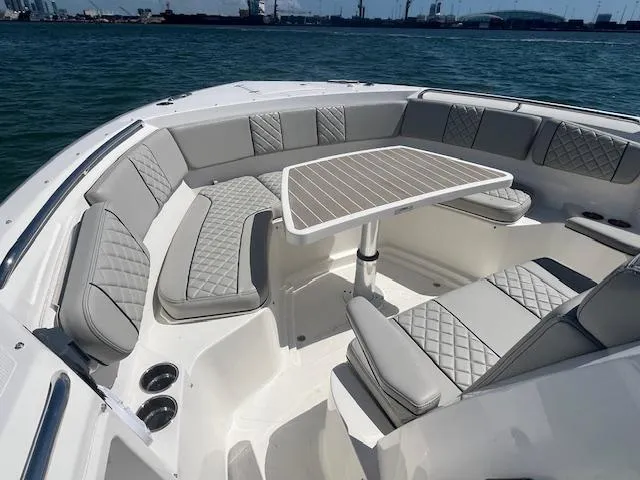 Slide: The Image of 2023 Pursuit S358 boat interior with cushioned seating and table on open water. - 19