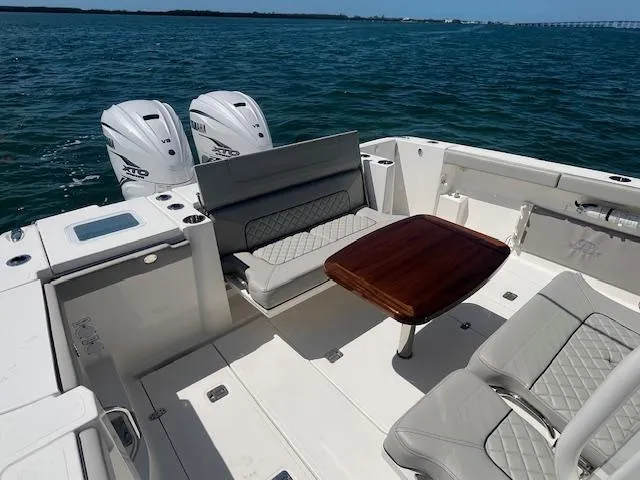 Slide: The Image of 2023 Pursuit S358 boat with dual engines, luxurious seating, and wooden table on open water. - 21