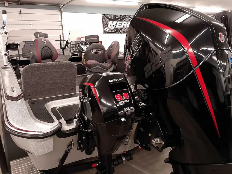 Slide: The Image of 2021 Triton 206 Allure boat with dual Mercury motors in a garage setting. - 2
