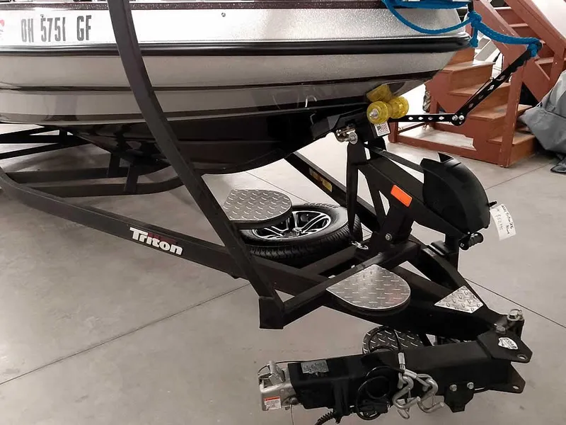 Slide: The Image of 2021 Triton 206 Allure boat trailer with hitch and spare tire in a garage. - 7