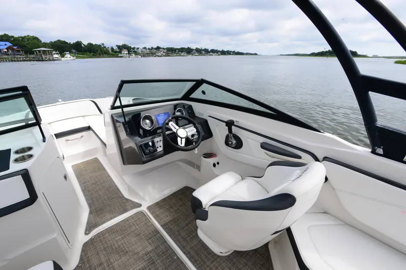 Slide: The Image of 2018 Sea Ray SPX 210 Outboard boat interior with steering wheel and seating on a calm lake. - 15