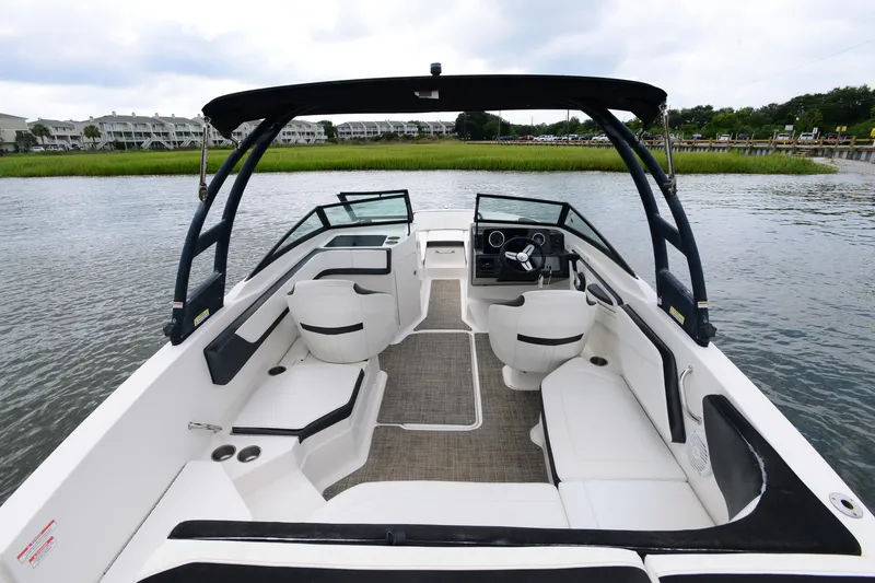 Slide: The Image of 2018 Sea Ray SPX 210 Outboard boat interior with seating and steering wheel on calm water. - 18
