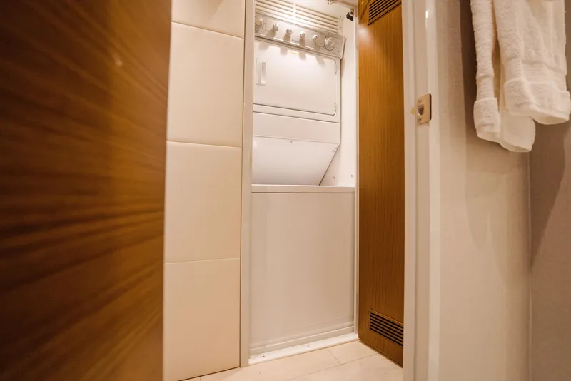 Slide: The Image of Laundry area inside 2017 Hatteras M75 Panacera yacht, featuring a compact washer and dryer. - 24