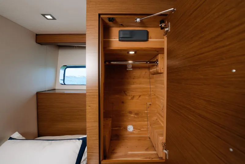 Slide: The Image of 2017 Hatteras M75 Panacera cabin with open wooden closet and window view. - 28