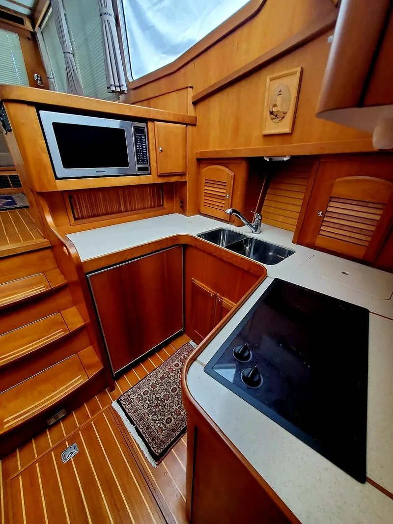 Slide: The Image of 2004 Sabre 36 Flybridge Fast Trawler kitchen with wood cabinetry, stove, and microwave. - 21
