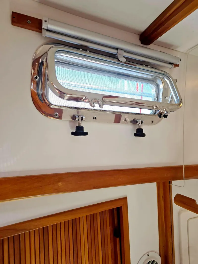 Slide: The Image of Port window inside 2004 Sabre 36 Flybridge Fast Trawler, featuring wood accents and metal frame. - 30