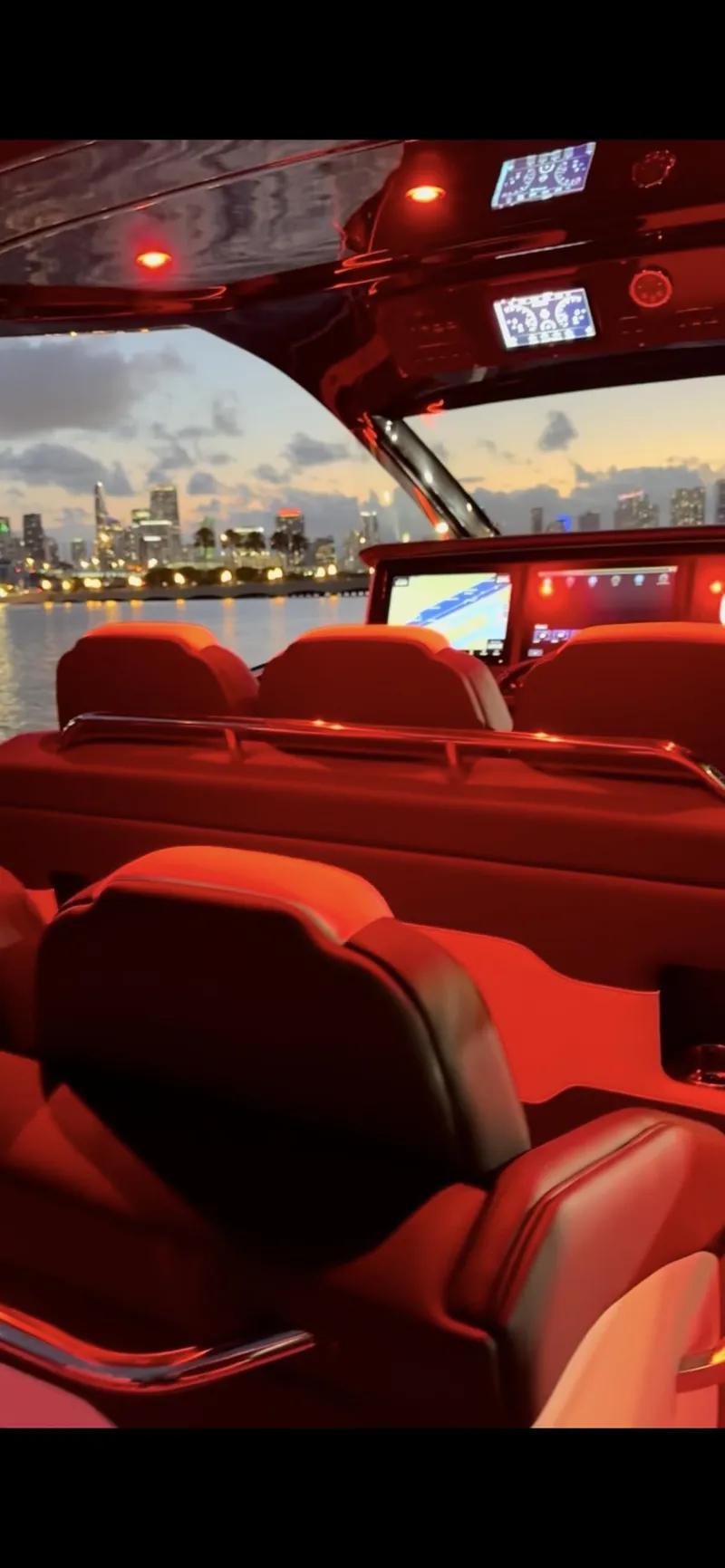 Slide: The Image of Interior of 2024 Cigarette 42 Auroris boat with red ambient lighting and city skyline view. - 17
