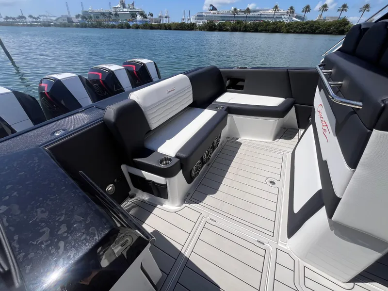 Slide: The Image of 2024 Cigarette 42 Auroris boat interior with seating, outboard engines, and waterfront view. - 6